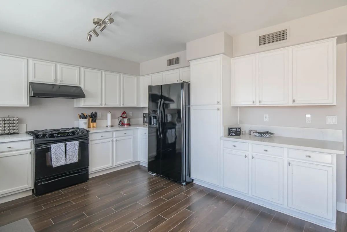 A welcoming kitchen with a black refrigerator, white cabinetry, and a central kitchen island, offering both workspace and social connection. The modern appliances and smart layout cater to groups and multiple cooks, reflecting the kitchen's role as a hub for culinary activity.