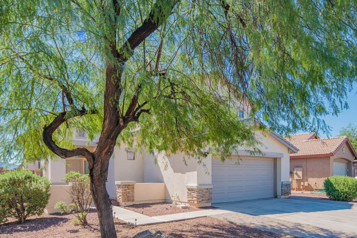 A welcoming driveway framed by a lush green tree and a well-maintained house facade. This exterior entryway sets the tone for arrival, suggesting a friendly neighborhood vibe and an inviting home base for exploring Metro Phoenix.