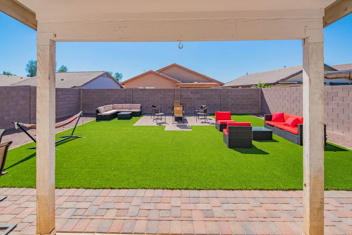 A laid-back outdoor space with a hammock, fire pit, red lounge chairs, and modern black outdoor furniture. The area invites relaxation and sociability, ideal for sunset gatherings or quiet afternoons under the sky.